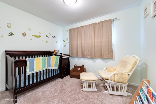 bedroom with baseboards, a crib, and carpet flooring