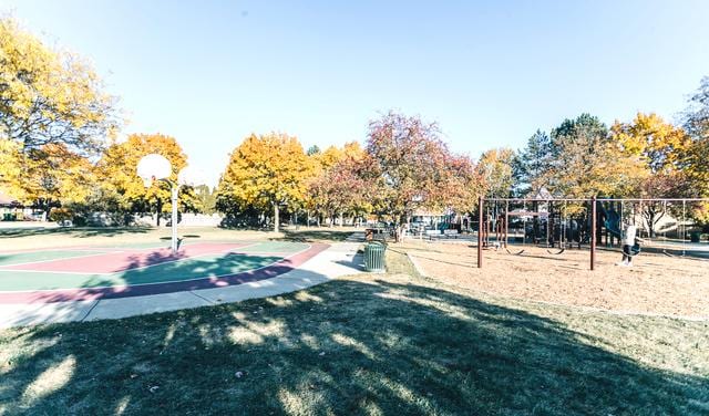 view of community with community basketball court, playground community, and a yard