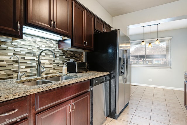 kitchen featuring light tile patterned floors, light stone countertops, a sink, dishwasher, and tasteful backsplash