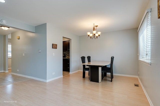 dining area with a notable chandelier, visible vents, a wealth of natural light, and light wood-type flooring