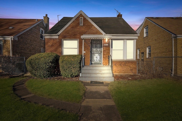 view of front of house featuring brick siding, a front lawn, and fence