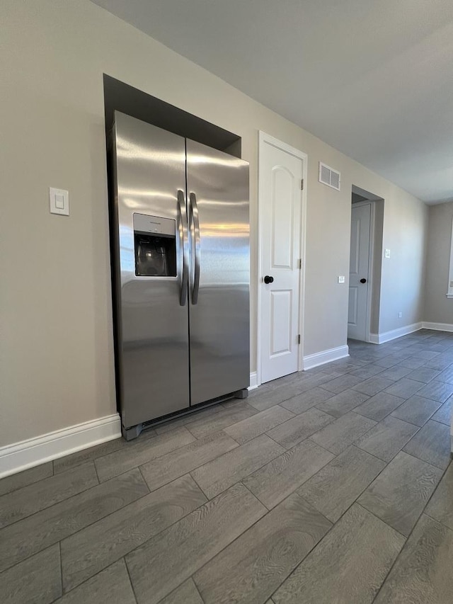 kitchen featuring visible vents, baseboards, wood tiled floor, and stainless steel refrigerator with ice dispenser