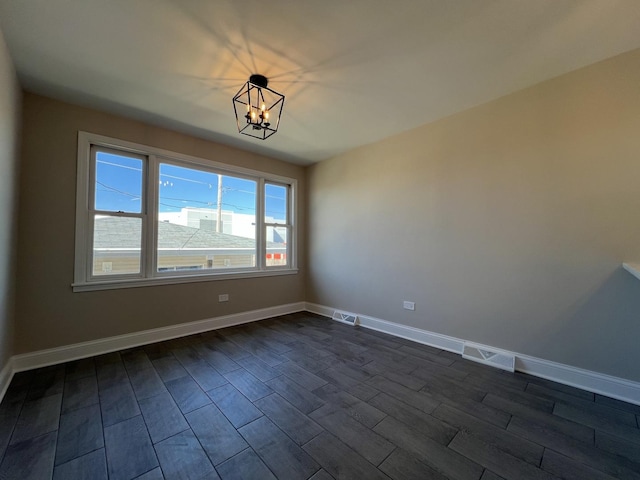 unfurnished room featuring visible vents, baseboards, dark wood-style floors, and a chandelier