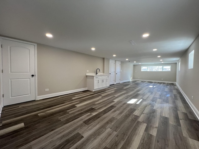 below grade area with recessed lighting, baseboards, dark wood-style floors, and a sink