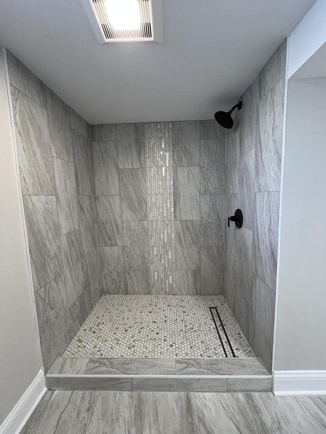 bathroom featuring visible vents, baseboards, and a tile shower