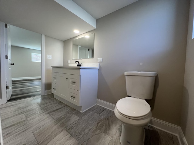 bathroom with baseboards, toilet, and vanity