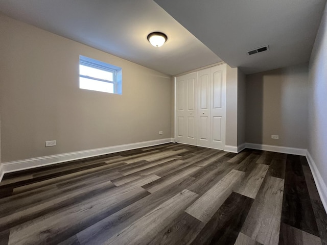 unfurnished bedroom featuring visible vents, baseboards, a closet, and dark wood-style flooring