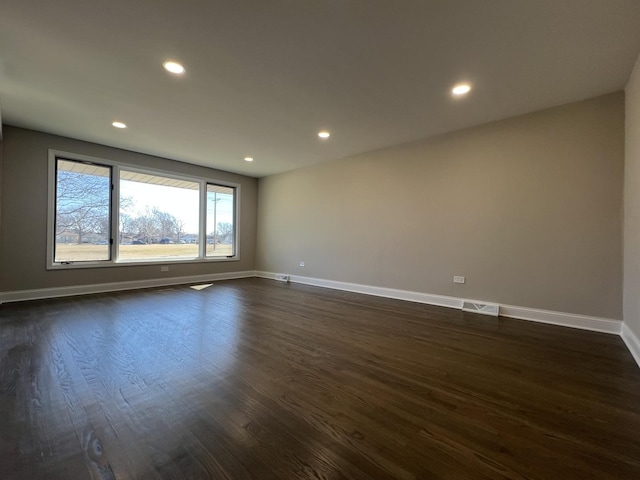 unfurnished room with visible vents, baseboards, and dark wood finished floors