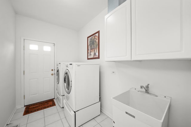 laundry area featuring light tile patterned floors, baseboards, cabinet space, a sink, and washer and dryer