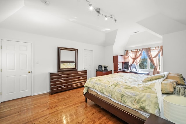 bedroom featuring lofted ceiling, baseboards, and light wood-type flooring