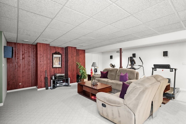 carpeted living room with baseboards and wood walls