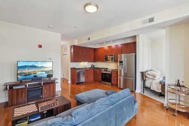 living room featuring visible vents, light wood-style floors, and track lighting