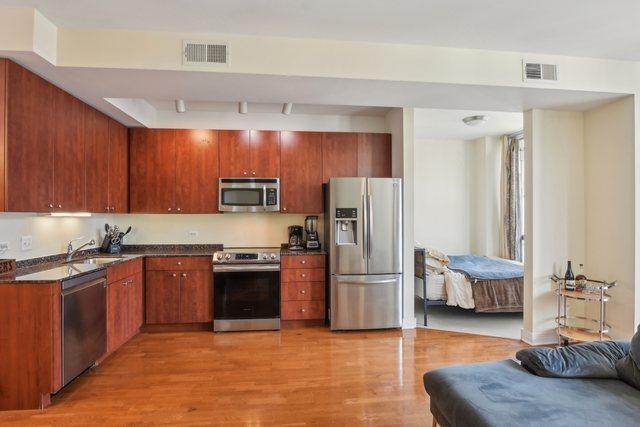 kitchen with a sink, stainless steel appliances, dark countertops, and visible vents