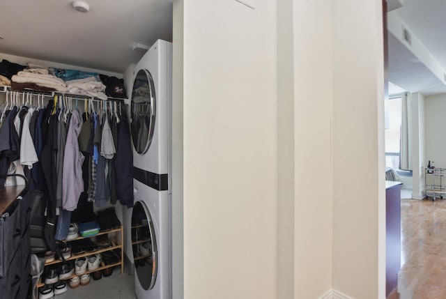 laundry area featuring laundry area, stacked washer / dryer, wood finished floors, and visible vents