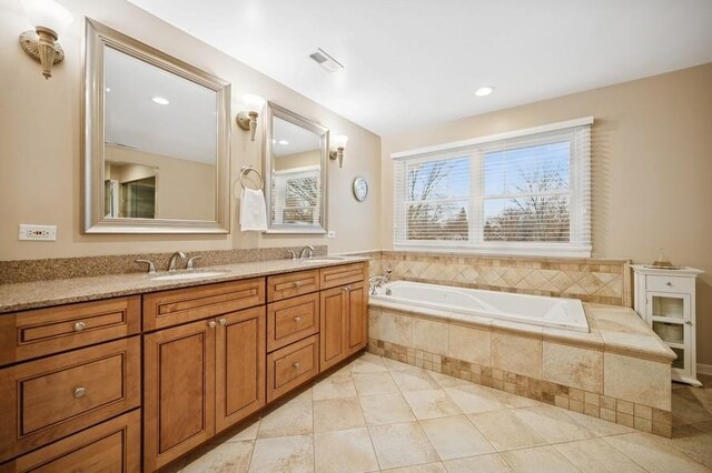 bathroom with a sink, visible vents, a garden tub, and double vanity