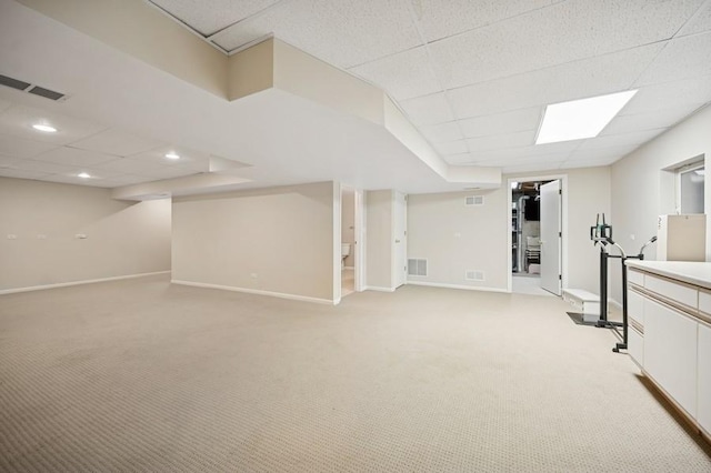 finished basement with light carpet, visible vents, and baseboards