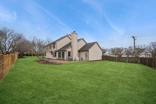 back of property with cooling unit, a lawn, a fenced backyard, and a chimney