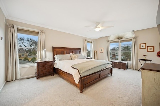 bedroom with ceiling fan, multiple windows, light colored carpet, and ornamental molding