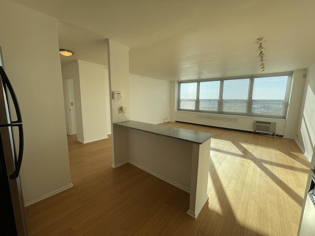 kitchen with a peninsula, freestanding refrigerator, baseboards, and wood finished floors