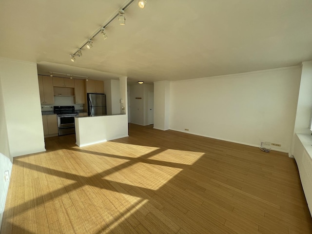 unfurnished living room with track lighting, baseboards, and wood finished floors