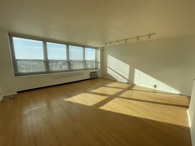 unfurnished room with rail lighting and wood-type flooring