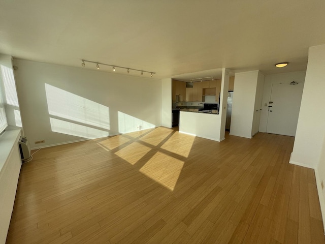 unfurnished living room with rail lighting, light wood finished floors, and a wall mounted AC