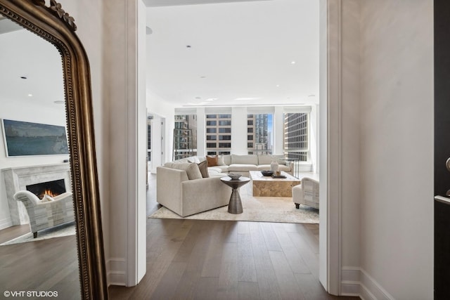 living area with dark wood-style floors, baseboards, and a high end fireplace