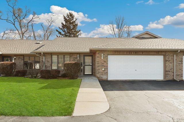 single story home featuring a front lawn, brick siding, a garage, and a shingled roof