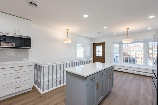 kitchen with visible vents, tasteful backsplash, baseboard heating, and wood finished floors