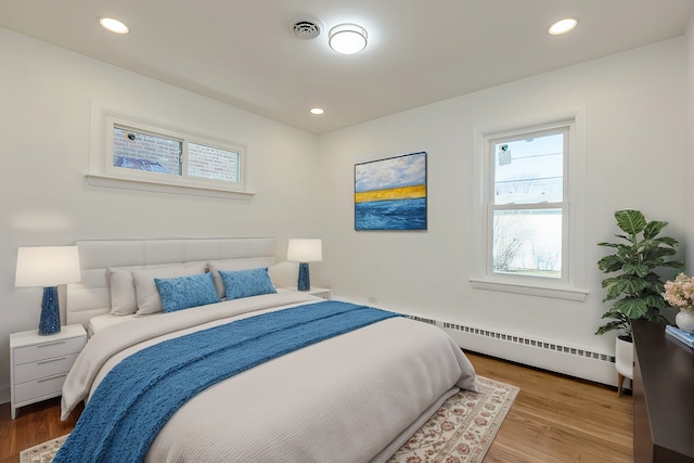 bedroom featuring visible vents, recessed lighting, a baseboard heating unit, and wood finished floors