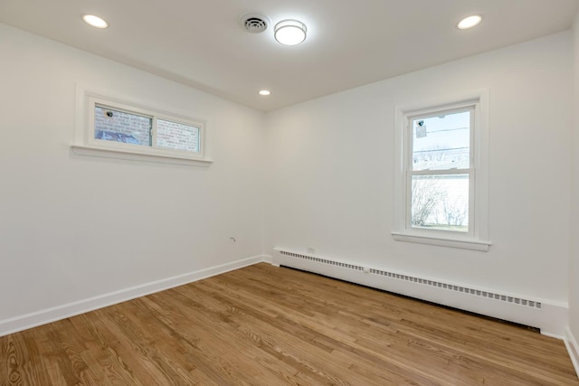 spare room with visible vents, baseboards, recessed lighting, wood finished floors, and a baseboard radiator