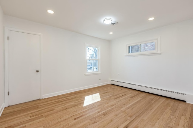 empty room featuring visible vents, a baseboard heating unit, recessed lighting, light wood-style floors, and baseboards