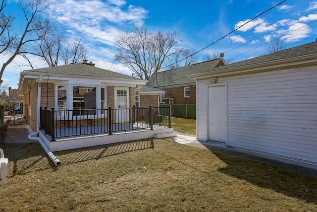 rear view of property with a wooden deck and a lawn