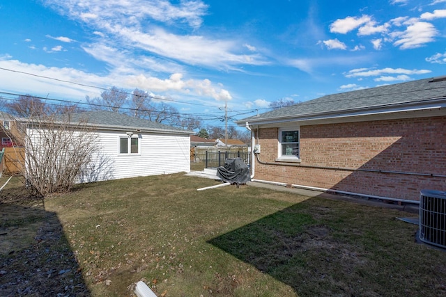 view of yard with central AC and fence