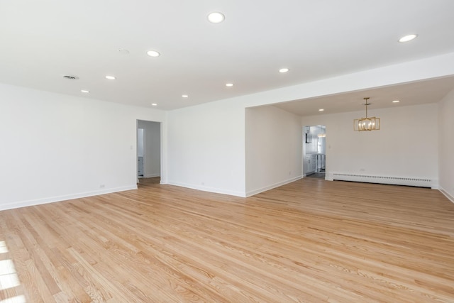 empty room featuring baseboards, a chandelier, light wood-type flooring, baseboard heating, and recessed lighting