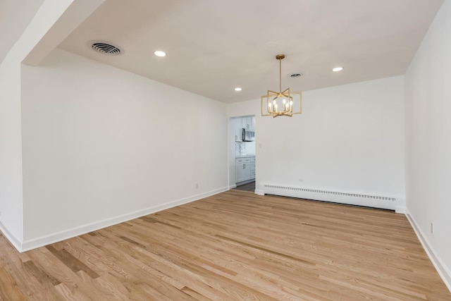 empty room featuring recessed lighting, light wood-style flooring, a baseboard heating unit, and baseboards