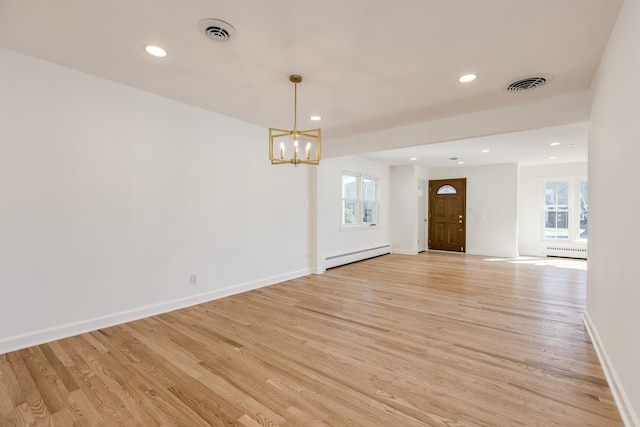 unfurnished room featuring a baseboard heating unit, light wood-style floors, and visible vents