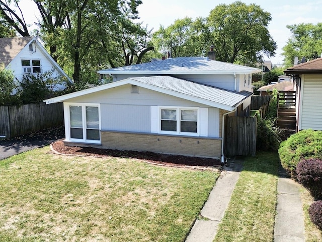 exterior space featuring fence, roof with shingles, a yard, a chimney, and brick siding