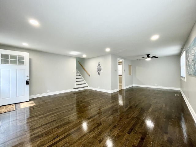 unfurnished living room with dark wood finished floors, stairway, recessed lighting, and baseboards