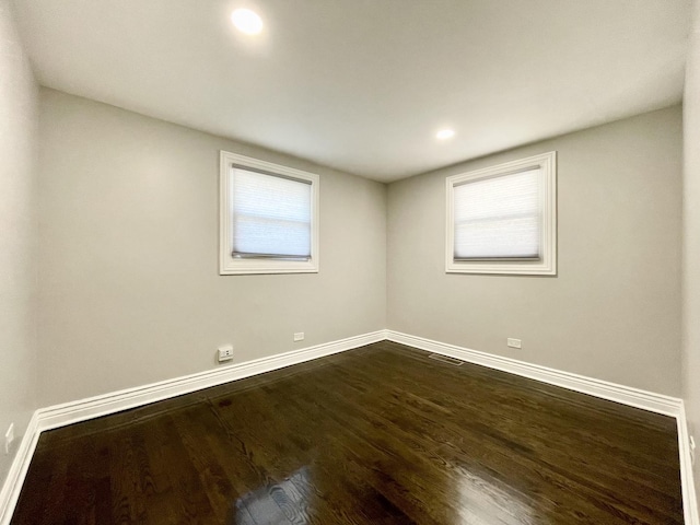 unfurnished room with dark wood finished floors, visible vents, recessed lighting, and baseboards