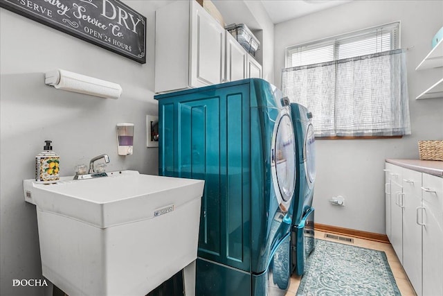 laundry room with visible vents, baseboards, separate washer and dryer, cabinet space, and a sink