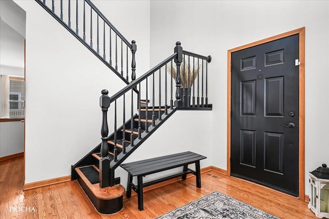 entryway with stairway, wood finished floors, and baseboards