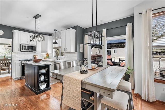 kitchen featuring light wood finished floors, light countertops, stainless steel appliances, a notable chandelier, and white cabinetry