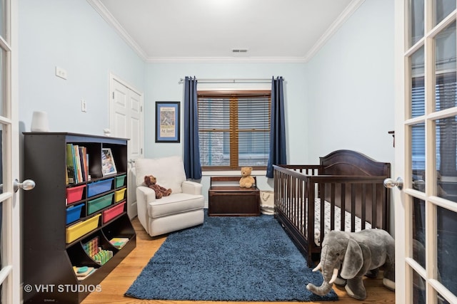 bedroom with visible vents, ornamental molding, wood finished floors, french doors, and a nursery area