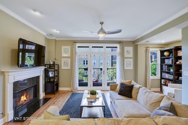 living area with a high end fireplace, crown molding, baseboards, and wood finished floors