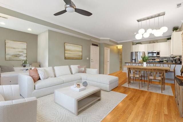 living room featuring visible vents, a ceiling fan, recessed lighting, light wood-style floors, and crown molding