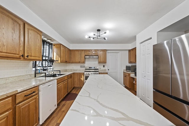 kitchen featuring a sink, brown cabinetry, wood finished floors, and stainless steel appliances