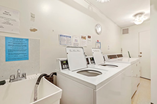 community laundry room with washing machine and clothes dryer, visible vents, and a sink