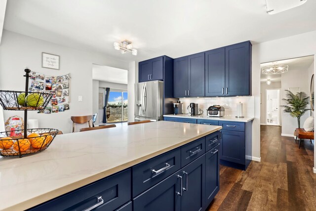 kitchen with blue cabinetry, dark wood-type flooring, tasteful backsplash, and stainless steel fridge with ice dispenser