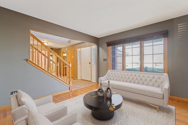 living area with stairs, wood finished floors, and baseboards